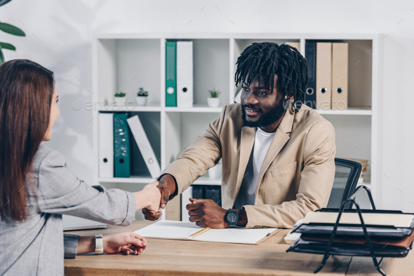 African american recruiter shaking hands with employee at job interview in office