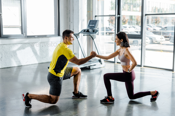 side view of sportsman and sportswoman doing lunges together in sports center