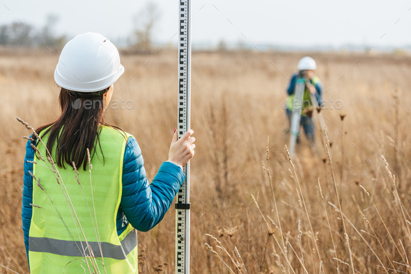 Selective focus of surveyors with survey ruler and digital level in field