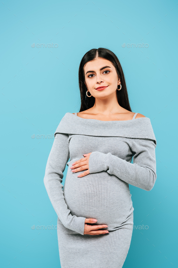 smiling pregnant pretty girl touching belly isolated on blue Stock Photo by  LightFieldStudios