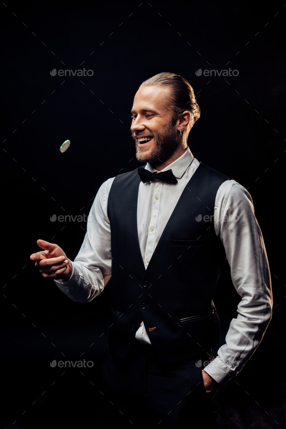happy bearded man throwing in air poker chip isolated on black