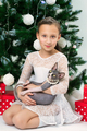 Portrait of girl 9 years old in white dress holding Sphynx Hairless Cat sits near Christmas tree - PhotoDune Item for Sale