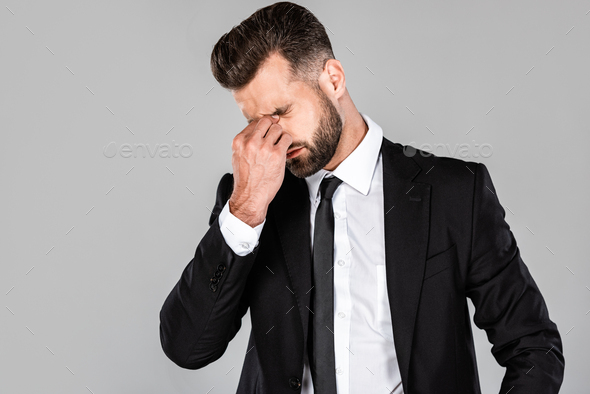 tired successful businessman in black suit rubbing his eyes isolated on grey