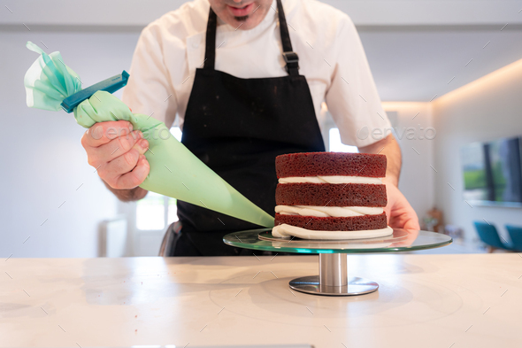 Man cooking a red velvet cake at home, triple sponge cake base with the pastry bag assembled