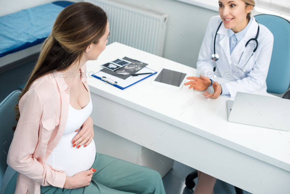 beautiful pregnant woman having consultation with gynecologist in clinic