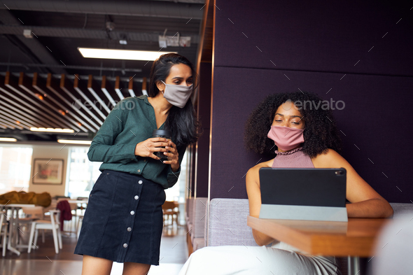 Businesswomen Wearing Masks Having Socially Distanced Meeting In Office During Health Pandemic