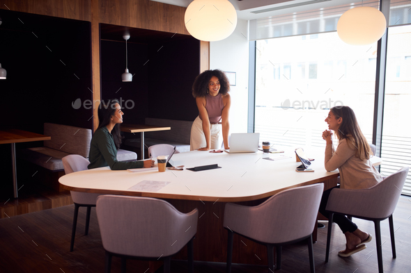 Three Businesswomen Having Socially Distanced Meeting In Office During Health Pandemic