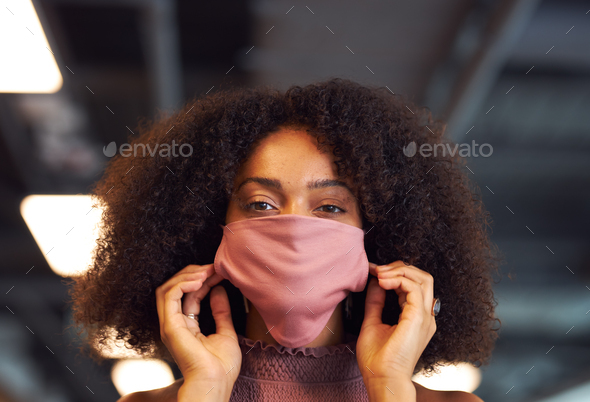 Portrait Of Businesswoman Putting On Face Mask In Modern Open Plan Office During Covid-19 Pandemic