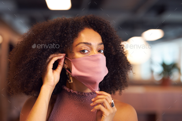 African woman putting on face mask