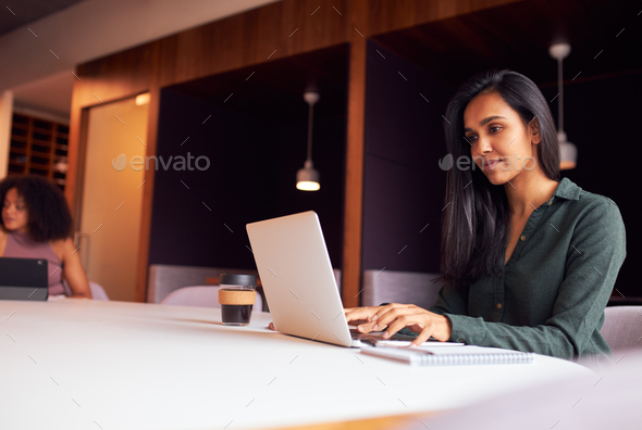 Businesswoman Working On Laptop At Socially Distanced Meeting In Office During Health Pandemic