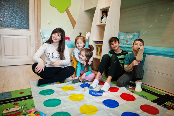 Happy family having fun together,four kids and mother playing twister game at home.