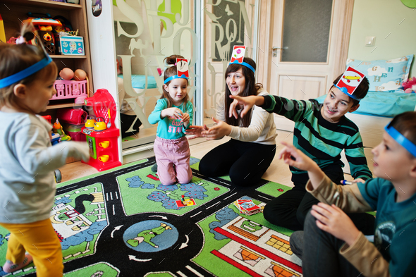 Happy family with four kids playing game guess who while having fun at home.