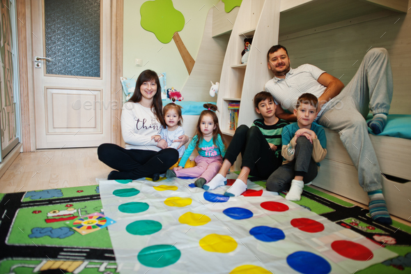 Happy big family having fun together,four kids playing twister game at home.