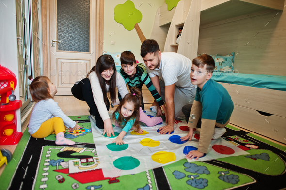 Happy big family having fun together,four kids playing twister game at home.