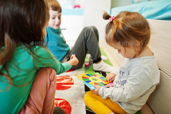 Happy family having fun together,four kids playing twister game at home.