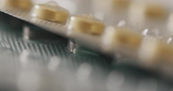 Video of close up of yellow tablets on pink background alt