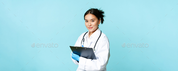 Healthcare and clinic concept. Smiling korean doctor, woman physician in medical uniform, holding