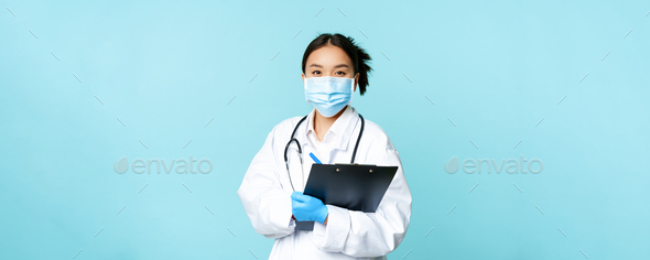 Covid-19 and quarantine concept. Smiling asian female physician, nurse in face mask holding