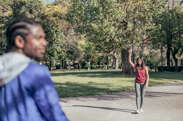 Just Friends. Girl Waving Hello Meeting Guy Walking In Park Outside. Selective Focus