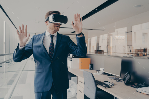 Businessman in virtual reality glasses standing near working desk in office