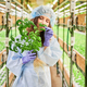 Woman gardener smelling leafy plant in greenhouse. - PhotoDune Item for Sale