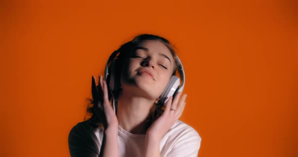 Happy Woman with Headphones Listening Music and Dance on the Colourful Background
