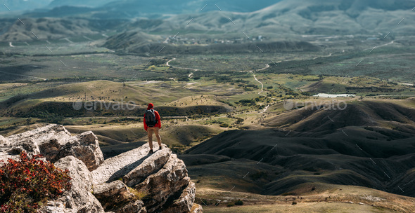 A traveler on the background of mountains. A tourist stands on top of a mountain - Stock Photo - Images