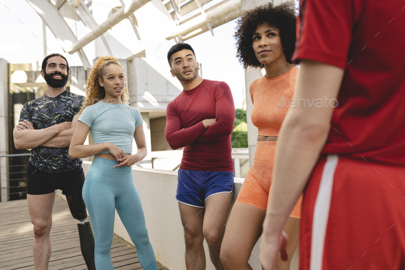 group of multiracial sportsmen standing resting while training together outdoors