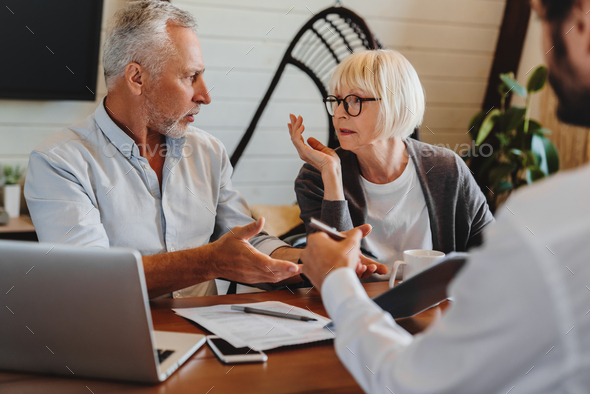 Financial advisor giving retirement advice to old couple while they arguing at home interior - Stock Photo - Images