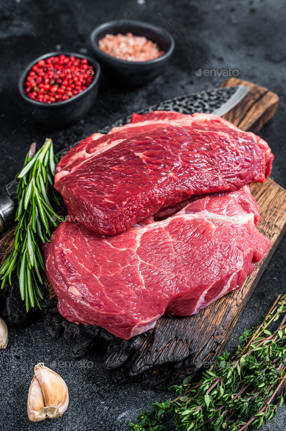 Raw Chuck eye roll Black Angus prime beef steak on butcher board with knife.