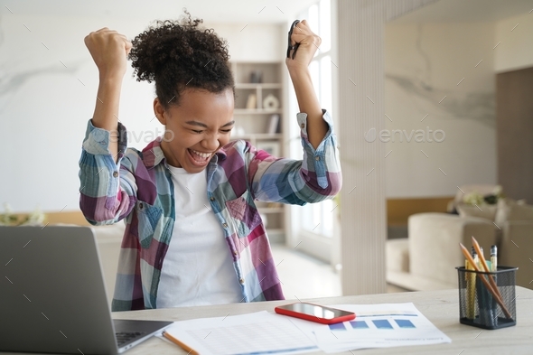 Excited african american teen girl received good news email on laptop screams, makes yes gesture