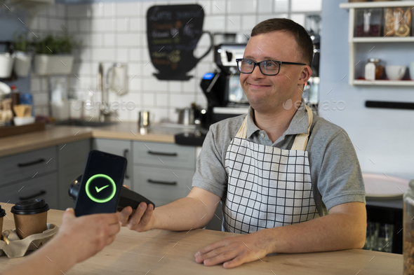Caucasian man with down syndrome doing contactless payment in the cafe
