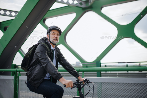 Businessman commuter on the way to work, riding bike over bridge, sustainable lifestyle concept.