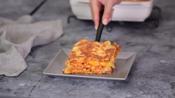 Piece of tasty hot lasagna on a gray plate. Homemade meat lasagna. Italian Traditional Food.