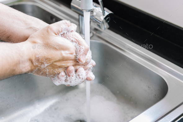 hands of a man washing in a pile with soap foam