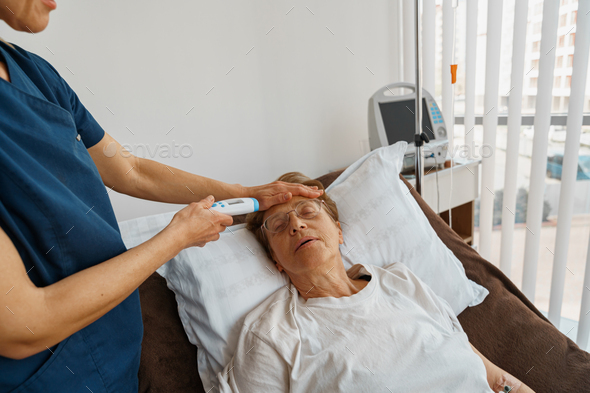 Close up of doctor measures patient\'s temperature with non-contact thermometer in hospital ward