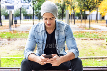 Outdoor portrait of modern young man with mobile phone in the street.