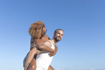 Couple piggy back on the beach in the summer
