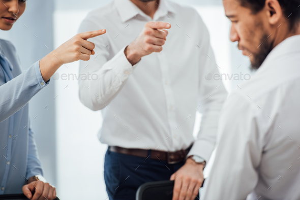 Selective focus of business people pointing with fingers at african american colleague