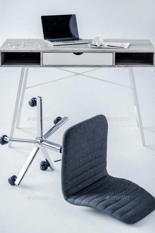 laptop on table and fallen empty office chair on white