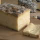 Piece of Italian Taleggio and a slice on a cutting board close up - PhotoDune Item for Sale