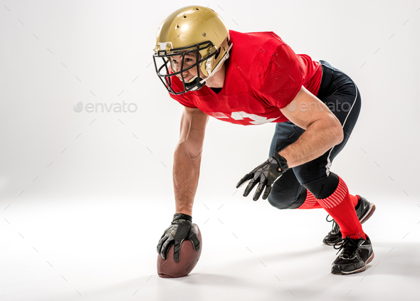 American football player in protective sportswear with ball isolated on grey