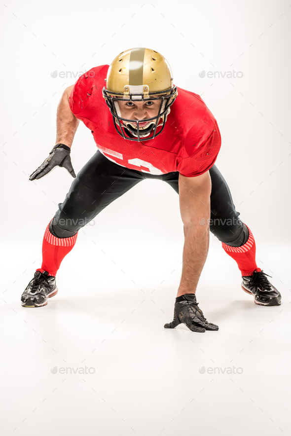 American football player in protective sportswear looking at camera isolated on grey