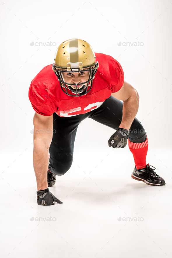 American football player in protective sportswear looking at camera isolated on grey