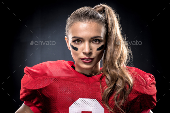 Attractive female american football player in uniform posing with