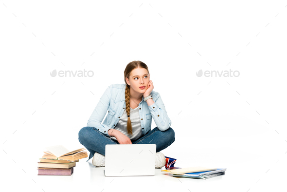pensive girl sitting on floor with laptop, books and copybooks and holding uk flag isolated on white