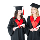 Two happy young women in academic gowns and mortarboards holding diplomas isolated on white - PhotoDune Item for Sale