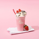 Disposable cup of milkshake with drinking straw, chocolate chips and strawberries on napkins on pink - PhotoDune Item for Sale