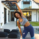 Cheerful young african american woman doing stretching exercise in backyard - PhotoDune Item for Sale