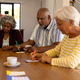 Multiracial senior friends with coffee cups on dining table playing bingo in nursing home - PhotoDune Item for Sale